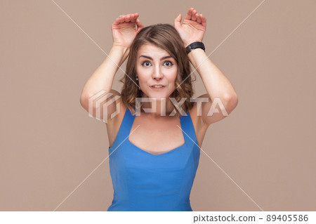 Comic woman showing rabbit sign at camera. Studio shot 89405586