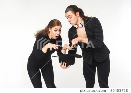 Wow! Magic inside hat. Man showing Imagination trick young woman. Studio shot, isolated on white background Wow! Magic inside hat. Man showing Imagination trick young woman. Studio shot, isolated on white background 89405728