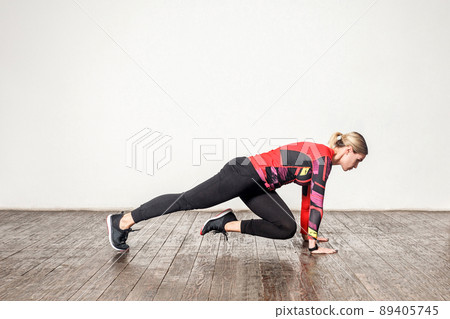 Side view of slim athletic woman in tight sportswear practicing yoga, doing plank bent leg, training flexibility, muscle strength. Health care, sports activity and workout at home. indoor studio shot 89405745