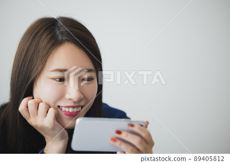 A woman watching a smartphone A woman watching a smartphone 89405812