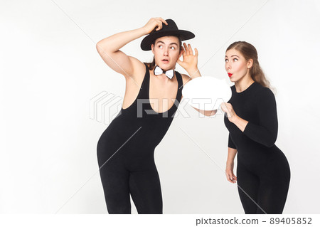 Young adult woman tells gossip in secret. Studio shot, isolated on white background Young adult woman tells gossip in secret. Studio shot, isolated on white background 89405852
