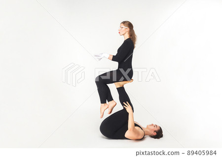 Acrobatic concept, sit pose. Young man holding woman legs, balancing. Studio shot, isolated on white background 89405984