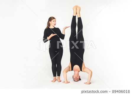 Vice versa. Woman showing at man, stand on head. Studio shot, isolated on white background 89406018