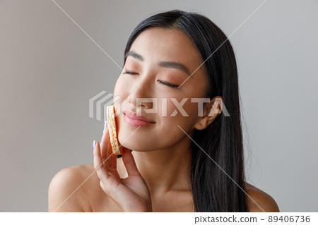Asian young woman cleaning face with cosmetic sponge Asian young woman cleaning face with cosmetic sponge 89406736