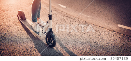Woman riding on scooter on asphalt road in summer Woman riding on scooter on asphalt road in summer 89407189