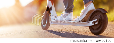 Woman riding on scooter on asphalt road in summer Woman riding on scooter on asphalt road in summer 89407190