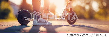 Woman riding on scooter on asphalt road in summer Woman riding on scooter on asphalt road in summer 89407191