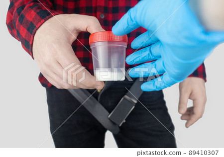 Man takes semen analysis. Spermogram. Concept. Male with his pants unbuttoned symbolizes preparation for analysis of seed for infertility, sperm motility. Suitability test for artificial insemination Man takes semen analysis. Spermogram. Concept. Male with his pants unbuttoned symbolizes preparation for analysis of seed for infertility, sperm motility. Suitability test for artificial insemination 89410307