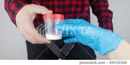 Man takes semen analysis. Spermogram. Concept. Male with his pants unbuttoned symbolizes preparation for analysis of seed for infertility, sperm motility. Suitability test for artificial insemination 89410308