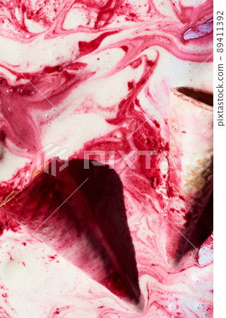 Close-up view of waffle cones lying in melted raspberry ice-cream with pink patterns Close-up view of waffle cones lying in melted raspberry ice-cream with pink patterns 89411392