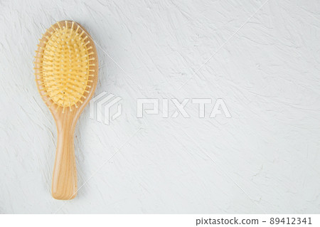 A wooden hair massager comb lies on a white textured background. High quality photo 89412341