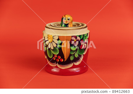 A small wooden doll inside a set of large matryoshkas. Open Traditional Russian symbol opposite the red background 89412663