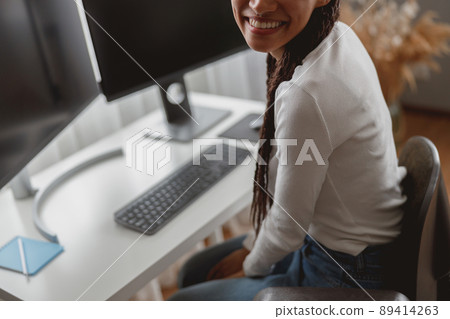 Close up of unrecognizable young positive woman indoor at table with computer monitors 89414263