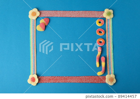 Photo frame made of gummy candies on blue background, space for text 89414457