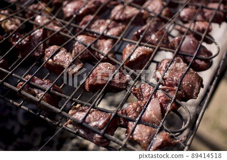 meat is fried on the grill over the coals 89414518