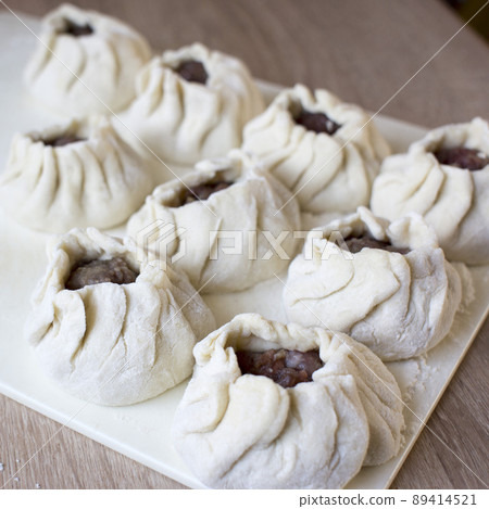 The process of making home-made dumplings. Raw homemade dumplings on a wooden board. Molding dumplings. 89414521