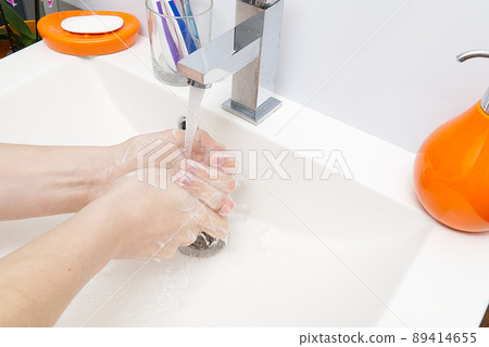 Washing of hands with soap under running water in white sink. close - up. antivirus protection wash your hands. Washing of hands with soap under running water in white sink. close - up. antivirus protection wash your hands. 89414655