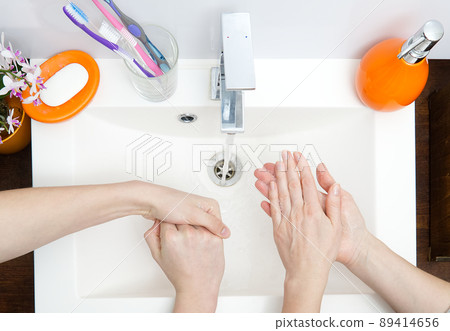 two people wash their hands with soap under running water in white sink. close - up. antivirus protection wash your hands. 89414656