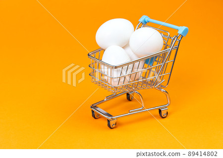 chicken white eggs in a shopping cart. isolated on orange chicken white eggs in a shopping cart. isolated on orange 89414802