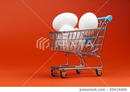 chicken white eggs in a shopping cart. isolated on orange 89414806