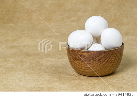 White Eggs isolated in wooden bowl on beige textured background 89414923