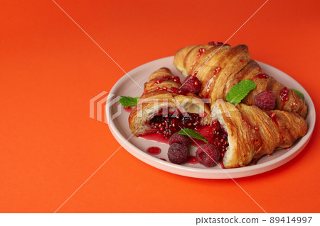 Plate with croissants with raspberry jam on orange background 89414997