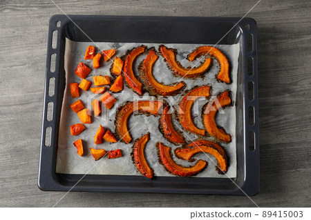 Baking tray with baked pumpkin on gray textured background Baking tray with baked pumpkin on gray textured background 89415003