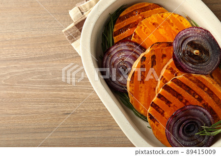 Baking tray with baked pumpkin on wooden background Baking tray with baked pumpkin on wooden background 89415009