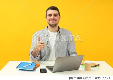 Study concept with young man sitting on the table on yellow background 89415571