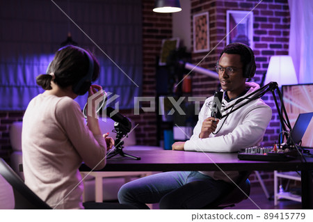 Diverse team of blog creators streaming podcast episode with recording and sound equipment. Man and woman meeting in studio to broadcast live discussion online, internet channel vlog. 89415779