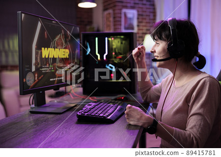 Happy woman winning video games tournament on live stream, using computer to have fun in rpg championship with multiple players. Female gamer celebrating action gameplay challenge win. Happy woman winning video games tournament on live stream, using computer to have fun in rpg championship with multiple players. Female gamer celebrating action gameplay challenge win. 89415781
