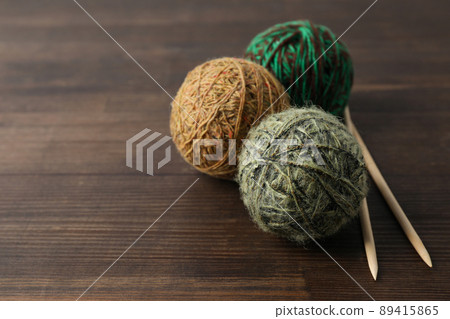 Multi colored balls of yarn with knitting needles on a wooden background Multi colored balls of yarn with knitting needles on a wooden background 89415865