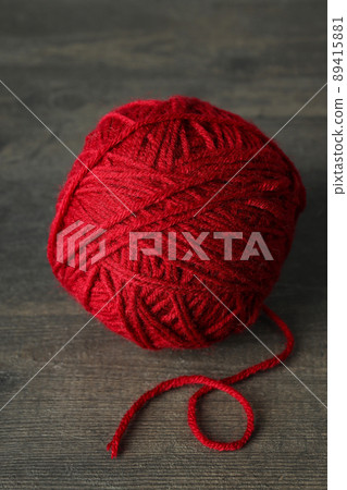 Red ball of yarn on gray wooden background. Red ball of yarn on gray wooden background. 89415881