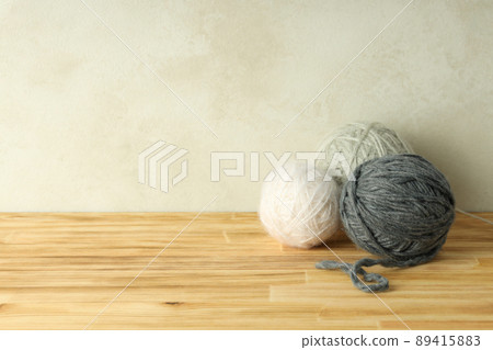 Multi colored balls of yarn on a light wooden table 89415883