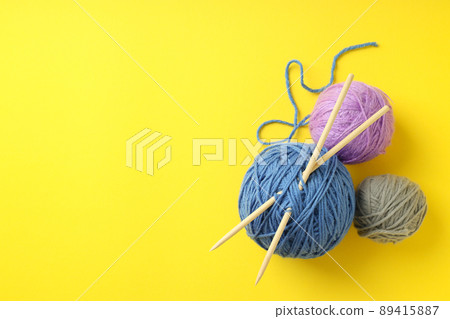 Multi-colored balls of yarn with knitting needles on yellow background Multi-colored balls of yarn with knitting needles on yellow background 89415887