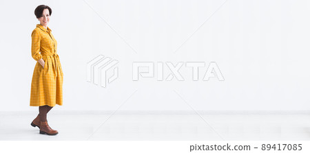 clothing, designer, people concept - attractive woman in a yellow dress posing on white room banner and place for advertising clothing, designer, people concept - attractive woman in a yellow dress posing on white room banner and place for advertising 89417085