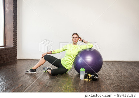 Weight loss. Many fitness equipment. Sporty woman relaxin on floor. Studio shot Weight loss. Many fitness equipment. Sporty woman relaxin on floor. Studio shot 89418188