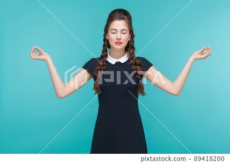 Meditating, zen practice. Young woman doing yoga. Indoor, studio shot on blue background 89418200