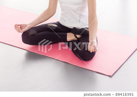 Anonymous woman sitting in lotus posture, doing yoga. Studio shot 89418391