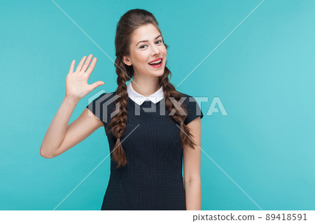 Happiness young budinesswoman showing hi sign. Indoor, studio shot on blue background 89418591