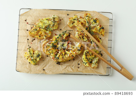 Baking rack with baked cauliflower and wooden tongs on white background Baking rack with baked cauliflower and wooden tongs on white background 89418693