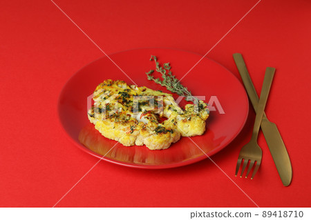 Concept of tasty eating with baked cauliflower on red background Concept of tasty eating with baked cauliflower on red background 89418710