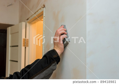 Contractor using sand trowel sanding the drywall Contractor using sand trowel sanding the drywall 89418981