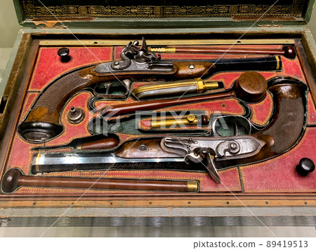 Two antique pistols with details are lying in a chest on red velvet. High quality photo 89419513