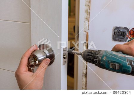 Builder in installing a door lock the door of a new house 89420504