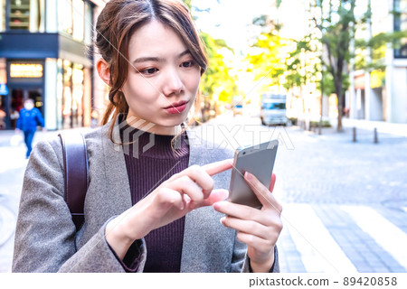 Tokyo Marunouchi, a young business woman checking a map on her smartphone 89420858