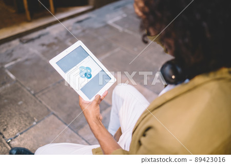 Cropped image of male holding touch pad downloading media file via application Cropped image of male holding touch pad downloading media file via application 89423016