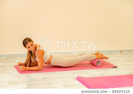 Fitness, pilates stretching exercises, a woman in beige sportswear, trains in a sports club. 89424110