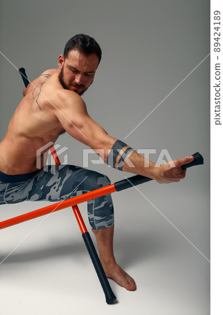 A ninja man holds on to a fighting stick and attacks close-up on gray studio background A ninja man holds on to a fighting stick and attacks close-up on gray studio background 89424189