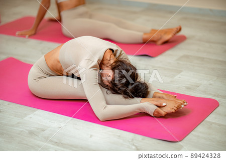 Fitness, pilates stretching exercises, a group of two attractive smiling mature women in beige sports clothes, train in a sports club. Fitness, pilates stretching exercises, a group of two attractive smiling mature women in beige sports clothes, train in a sports club. 89424328